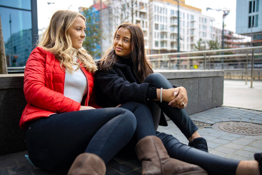 Portrait Of Two Smiling Female Friends Looking at Each Other In City