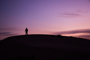 Silhouette of a man standing on a dune at sunrise