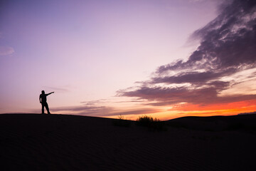 Fototapeta na wymiar Silhouette of an unrecognizable man pointed the finger at sunset in the desert