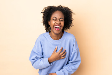 Fototapeta premium Young African American woman isolated on beige background smiling a lot