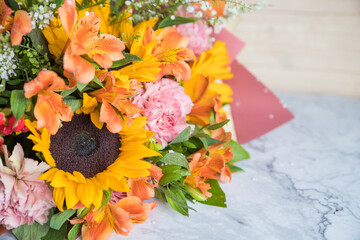 Fresh Bouquet of yellow sunflowers and pink carnations on marble background. flower shop. A variant of a bouquet on an autumn theme, for Thanksgiving.