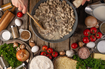 The cook fries mushrooms in a skillet. The ingredients are on the table side by side. Filling for pizza, ravioli, pasta, pie. Cookbook, home cooking, restaurant, hotel, menu design.