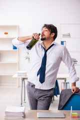 Young alcohol addicted employee sitting in the office