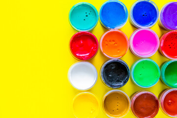 Many bright cans of paint stand together on a yellow background with a place for text. top view, flat lay, copy space, isolate.