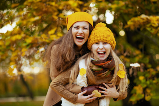 mom and child outdoors on city park in autumn having fun time
