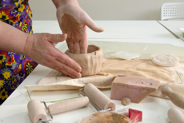 Woman hand potter making clay cup in pottery workshop studio. Process of creating ceramic mug. Handmade, hobby art and handicraft concept.