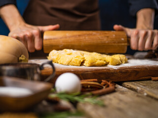 The chef rolls out the pumpkin pie dough with a rolling pin. The classic recipe. Ingredients. Close-up. Country style. Thanksgiving, Halloween, New Years, Christmas, family holidays.