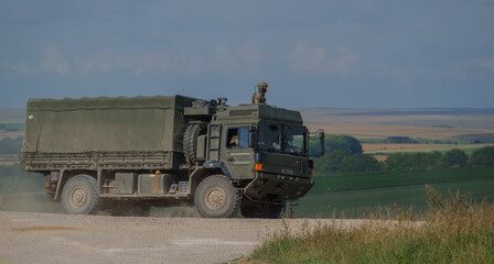 Fototapeta premium British army MAN SV 4x4 army lorry logistics vehicle truck with soldier security look-out on a dirt track in action on a military exercise, Salisbury Plain UK