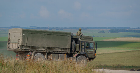 Fototapeta premium British army MAN SV 4x4 army lorry logistics vehicle truck with soldier security lookout on a dirt track in action on a military exercise, Salisbury Plain UK