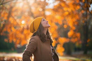 happy trendy woman in brown coat and yellow hat - obrazy, fototapety, plakaty