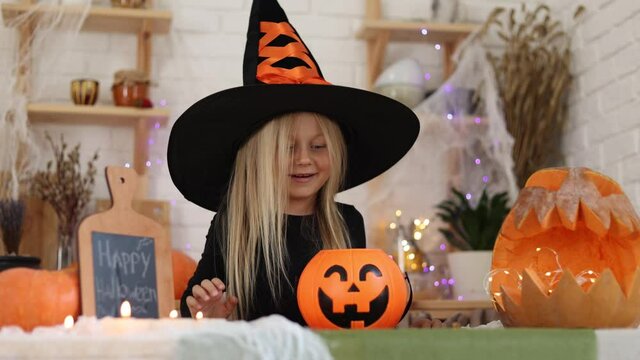 cute little girl blonde in a witch costume on Halloween smiles looking into the camera. high quality video footage. High quality 4k footage