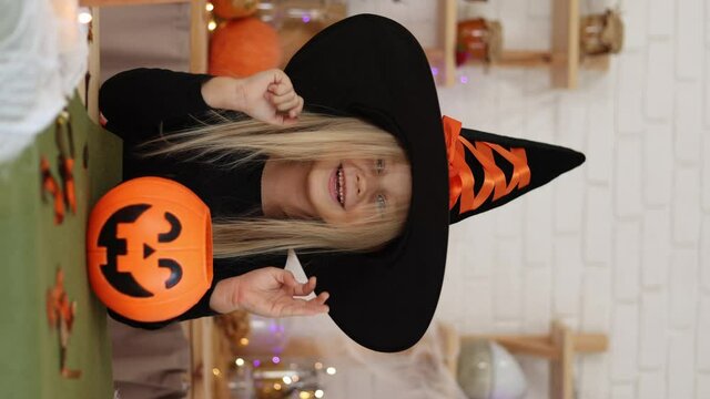 cute little girl blonde in a witch costume on Halloween smiles looking into the camera. high quality video footage. High quality 4k footage