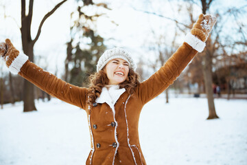 happy modern woman rejoicing outdoors in city park in winter