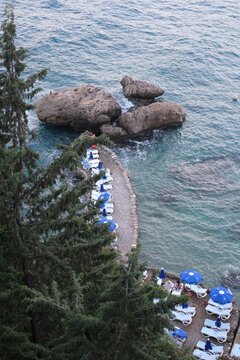 Drone shot of a beautiful view of a several beach shezlongs on the beach and the blue sea