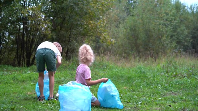 children remove plastic garbage and put it in a biodegradable garbage bag in the open air. The concept of ecology, waste processing and nature protection. Environmental protection