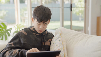 Fototapeta na wymiar Mixed Asian preteen teen boy making video calling with digital tablet at home, using zoom online virtual class , social distancing, homeschooling, remote learning, new normal concept
