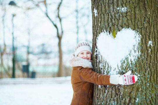 happy modern child hugging tree with snowy heart