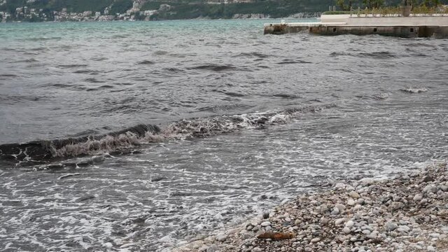 Black muddy waves of healing sea mud on a mud beach, or a black beach in Igalo, Montenegro. The beach in front of the spa building in Igalo