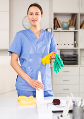 Portrait of a girl with cleaning agent and gloves in her hands, who is going to clean up the office