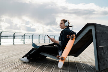 The freelancer is stylish in a hat in the city. A young hipster man listens to music with headphones. A teenager responds to friends in a message on a smartwatch social network.