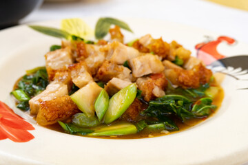 Selective Focus Stir fried chinese kale with crispy pork on red table