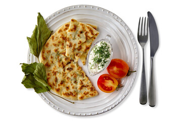 Flatbreads with cheese and herbs and yogurt sauce on a white plate with cutlery