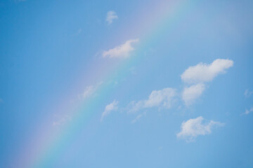 Naklejka na ściany i meble Beautiful Rainbow with blue sky behind and clouds after a thunderstorm