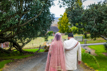 Indian married couple in wedding outfit walking back view