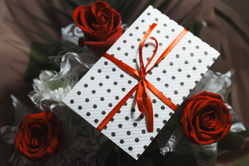 3 red roses  bouquet with gift envelope, red ribbons, white paper for certificates, invitation card inside. Craft concept. Red on the red background.   Weddig, ceremony concept, holidays, surprises.