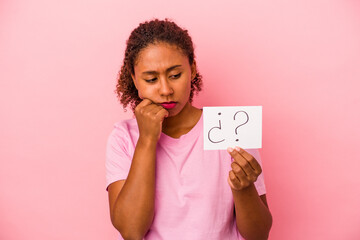 Young African American woman holding a question placard isolated on pink background