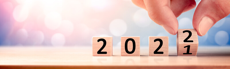 Hand Changing Date On Wooden Cube Calendar From 2021 To 2022 - New Years Concept