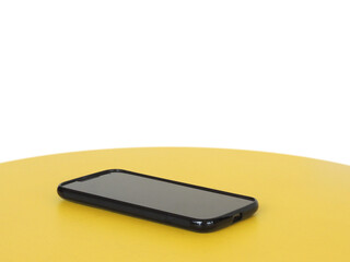 Mobile phone isolated on a yellow table in perspective. 