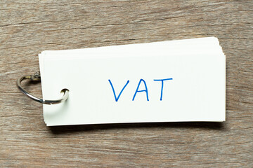 Flash card with handwriting word VAT (abbreviation of value added tax) on wood background