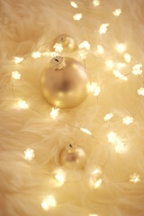 Christmas background with shining garland and golden balls on beige fur in warm colors. Winter cozy mood.Winter holidays background.Warm winter background. 