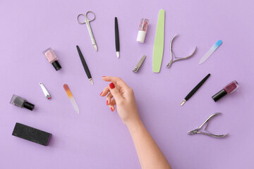 Female hand and tools for manicure on lilac background
