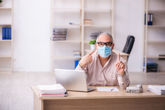 Old Male Employee Working At Workplace During Pandemic