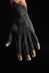 Fototapeta premium Male hand covered with black and golden paint on dark background