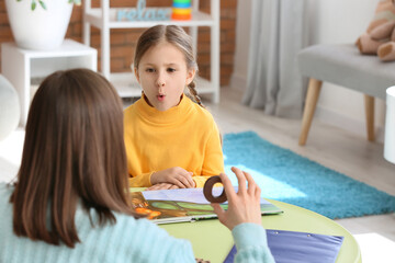 Speech therapist working with cute girl in clinic