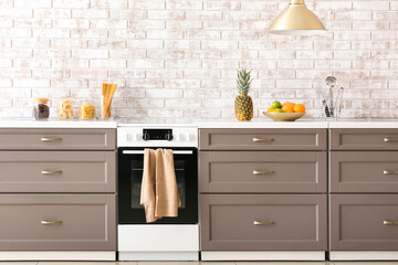 Modern furniture with electric oven near brick wall
