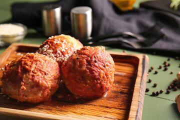 Board with delicious meatballs on color wooden background
