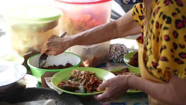 An Indonesian old woman is preparing "Gado Gado" for customers. Gado gado is a Traditional food from Indonesia