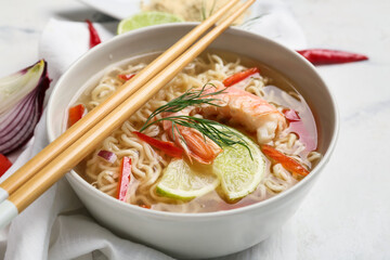 Bowl of tasty Thai soup with shrimps on light background, closeup