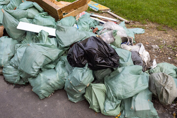 Construction garbage. Garbage bags next to lawn. Waste from construction works. Lots of polypropylene bags in landfill. Bunch of rubbish. Garbage bags sale concept. Disposal of construction waste