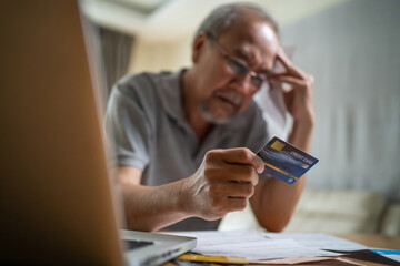 Depressed Asian Senior male feeling worried about financial problem. 