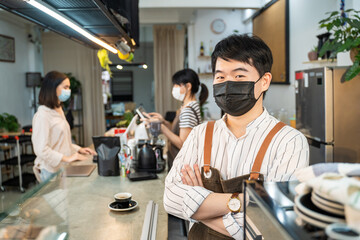 Portrait of Asian waiter worker wear mask and look at camera at cafe. 