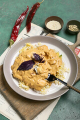 Plate of tasty chicken curry with rice on color background