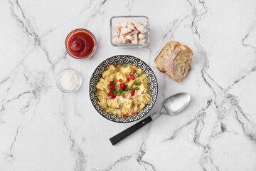 Bowl of tasty chicken curry and ingredients on light background