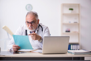 Old male doctor working in the clinic