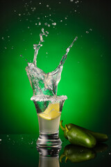 Shot of tasty tequila with jalapeno peppers on color background