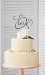 Stand with delicious wedding cake and word LOVE on light background, closeup